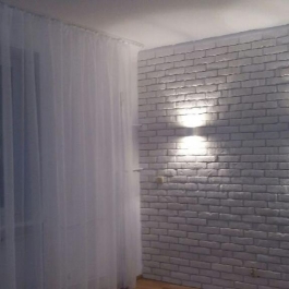 Surowe wykończenie w postaci białej cegły. Lokalizacja mieszkania: Warszawa. Wykonaliśmy remont salonu.